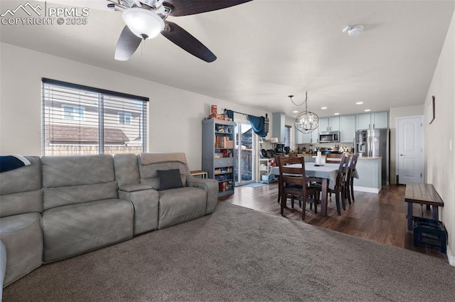 living room with dark hardwood / wood-style floors and ceiling fan with notable chandelier