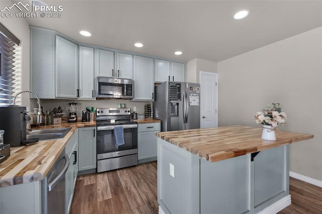 kitchen with a center island, appliances with stainless steel finishes, sink, and butcher block countertops