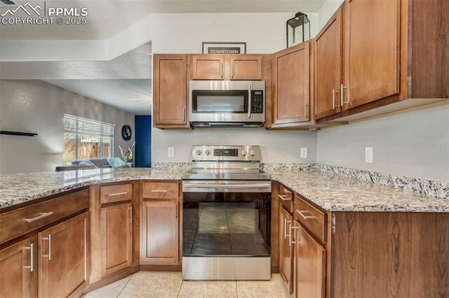 kitchen with light stone counters, appliances with stainless steel finishes, light tile patterned flooring, and kitchen peninsula