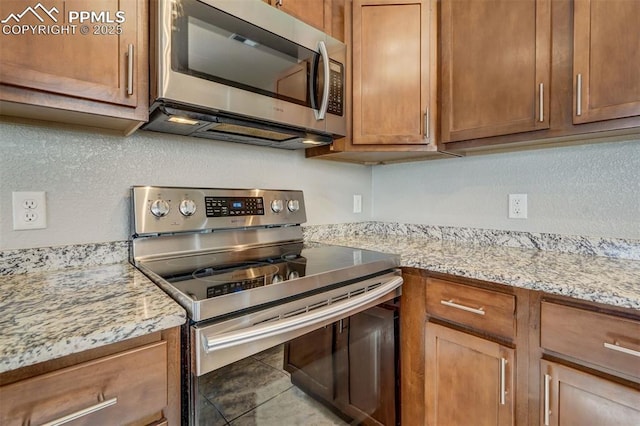 kitchen featuring light stone counters, appliances with stainless steel finishes, and tile patterned flooring