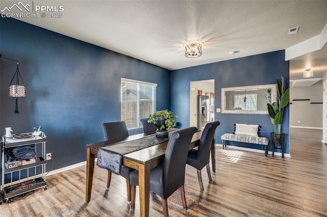 dining room with hardwood / wood-style flooring and a textured ceiling