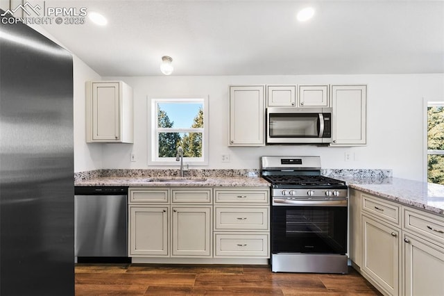 kitchen featuring light stone countertops, appliances with stainless steel finishes, sink, and dark hardwood / wood-style floors