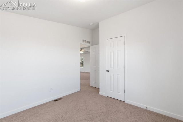 spare room featuring lofted ceiling and light colored carpet