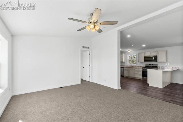 unfurnished living room featuring sink, dark carpet, and ceiling fan