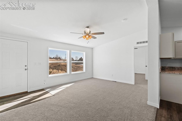 unfurnished living room featuring ceiling fan and dark carpet