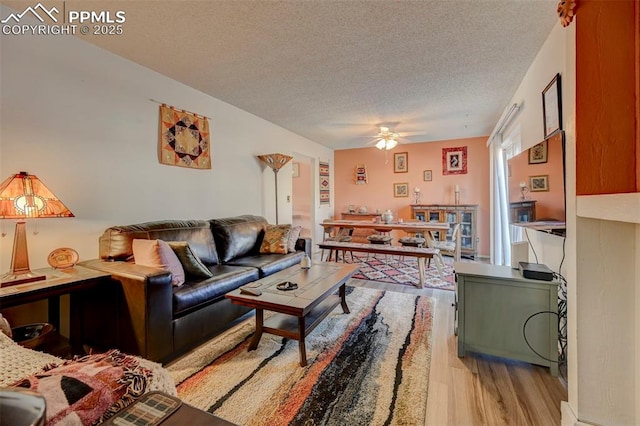 living room featuring ceiling fan, a textured ceiling, and light hardwood / wood-style flooring