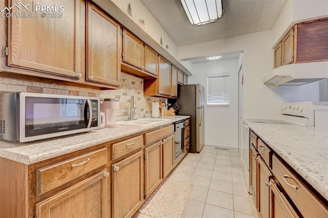 kitchen featuring light tile patterned flooring, sink, decorative backsplash, stainless steel appliances, and a textured ceiling