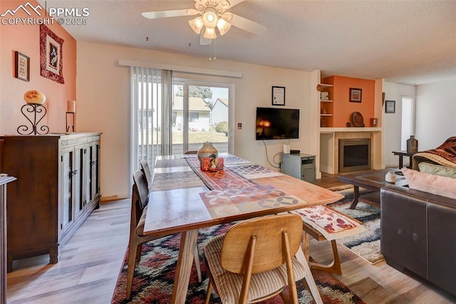 dining area with ceiling fan, light wood-type flooring, and a textured ceiling