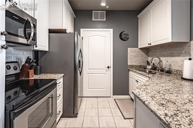 kitchen with light stone countertops, white cabinetry, appliances with stainless steel finishes, and sink