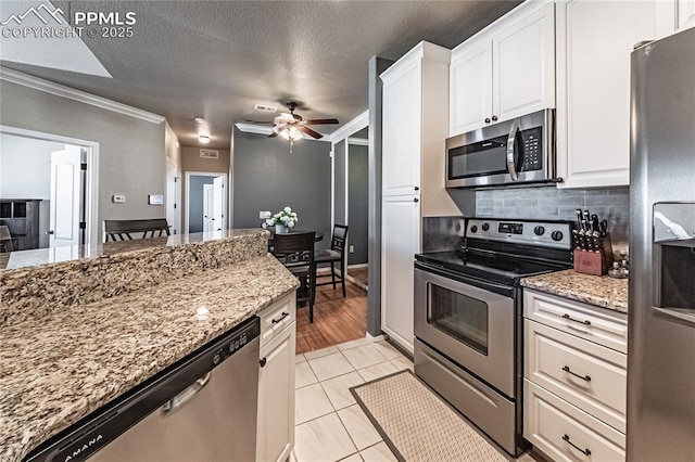 kitchen with white cabinetry, tasteful backsplash, light stone countertops, and appliances with stainless steel finishes