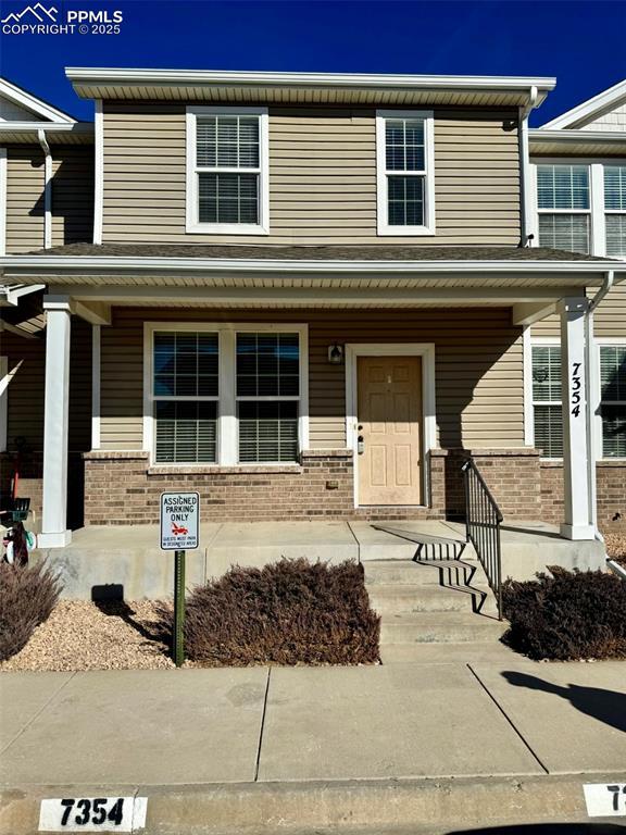 multi unit property featuring a porch and brick siding