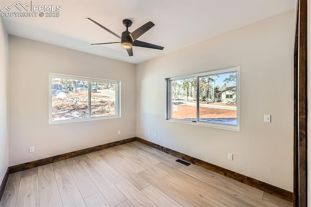 spare room with ceiling fan, a wealth of natural light, and light wood-type flooring