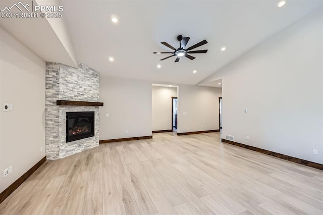 unfurnished living room featuring vaulted ceiling, a stone fireplace, ceiling fan, and light hardwood / wood-style floors