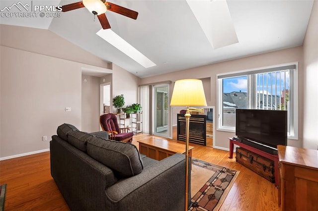 living room with hardwood / wood-style flooring, ceiling fan, and lofted ceiling with skylight