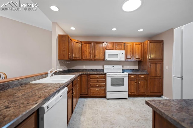 kitchen featuring sink, white appliances, and dark stone counters