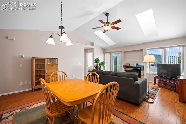 dining area featuring a high end fireplace, vaulted ceiling with skylight, ceiling fan, and wood-type flooring