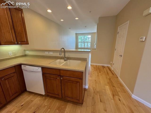 kitchen with sink, light hardwood / wood-style flooring, kitchen peninsula, and dishwasher