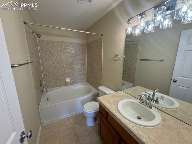 full bathroom with tile patterned flooring, vanity, tiled shower / bath combo, and toilet