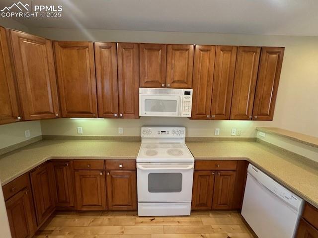 kitchen with white appliances and light hardwood / wood-style flooring