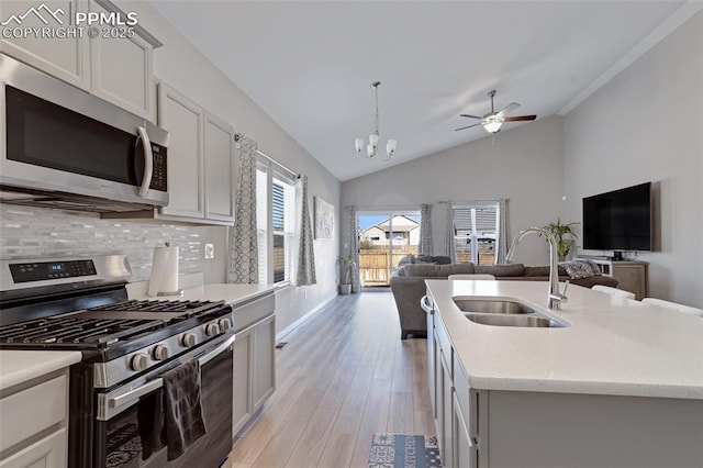 kitchen with appliances with stainless steel finishes, pendant lighting, tasteful backsplash, an island with sink, and sink