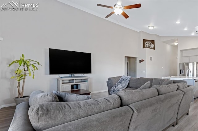 living room with ceiling fan, vaulted ceiling, and light hardwood / wood-style flooring