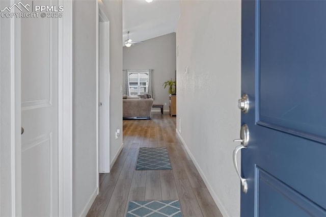 hall with lofted ceiling and light hardwood / wood-style floors