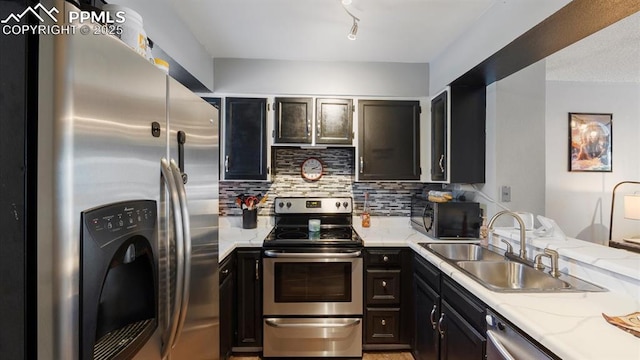 kitchen with light stone countertops, appliances with stainless steel finishes, sink, and backsplash