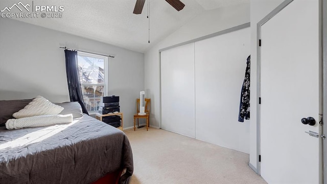 bedroom with light colored carpet, vaulted ceiling, a textured ceiling, a closet, and ceiling fan