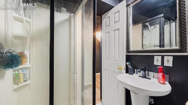 bathroom with a shower with door and sink