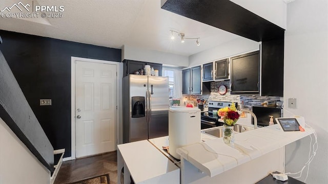 kitchen with appliances with stainless steel finishes, sink, backsplash, kitchen peninsula, and light stone countertops