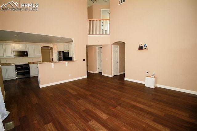 kitchen featuring white cabinetry, double oven range, kitchen peninsula, black fridge, and dark wood-type flooring