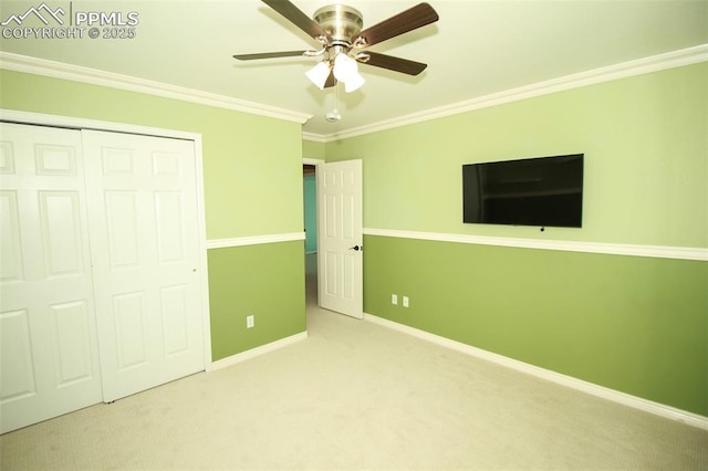 unfurnished bedroom with crown molding, light colored carpet, ceiling fan, and a closet