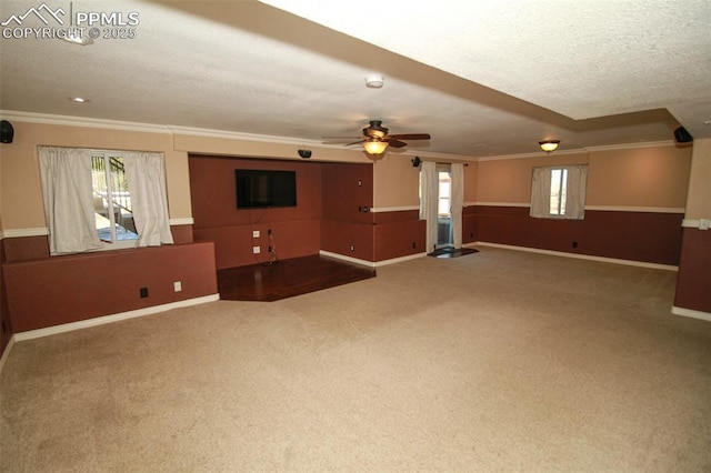 unfurnished living room featuring ceiling fan, crown molding, a textured ceiling, and carpet flooring