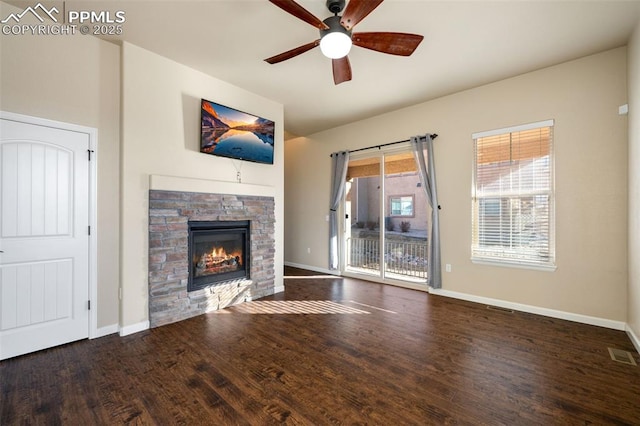 unfurnished living room with dark hardwood / wood-style floors, ceiling fan, and a stone fireplace