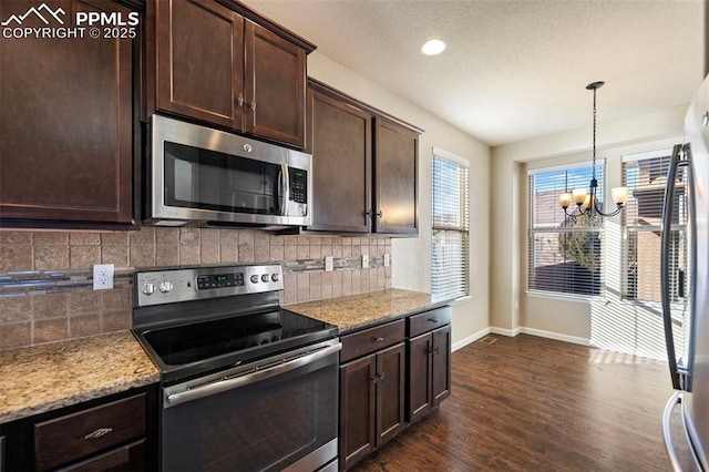 kitchen with dark brown cabinetry, light stone counters, pendant lighting, and appliances with stainless steel finishes