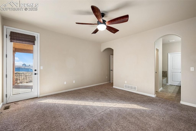 carpeted empty room featuring ceiling fan and a water view