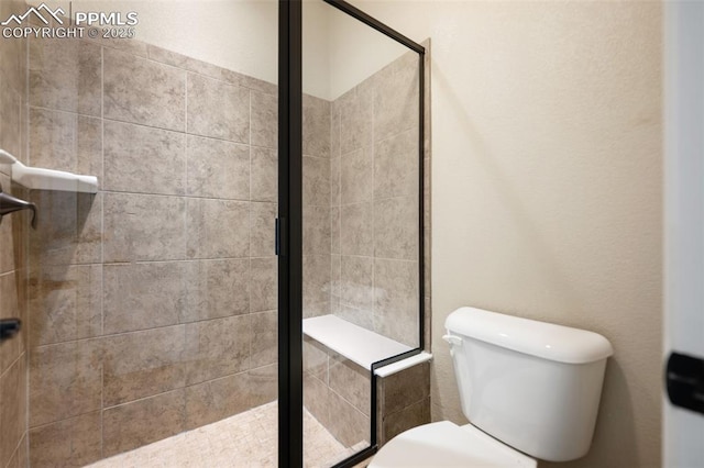 bathroom featuring a shower with shower door and toilet