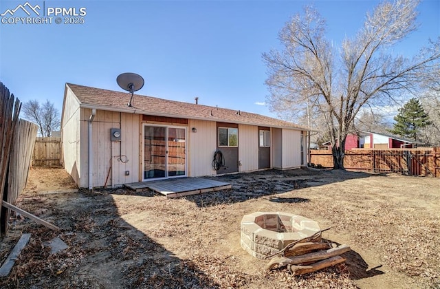 back of house featuring a fenced backyard and a fire pit