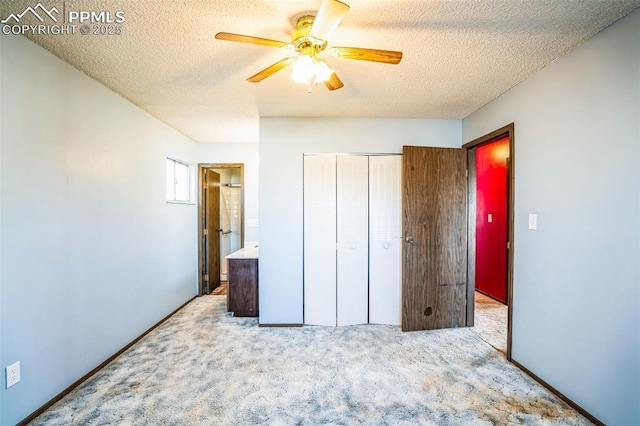 unfurnished bedroom featuring ceiling fan, connected bathroom, a textured ceiling, light colored carpet, and a closet