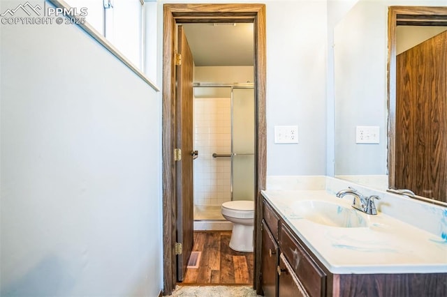 bathroom with a shower with door, vanity, hardwood / wood-style flooring, and toilet