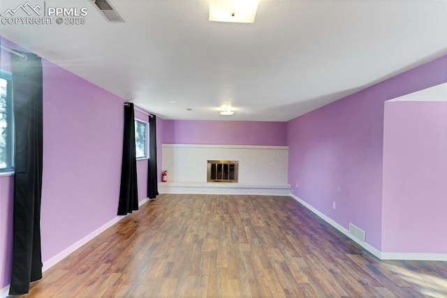 unfurnished living room with a brick fireplace and hardwood / wood-style floors