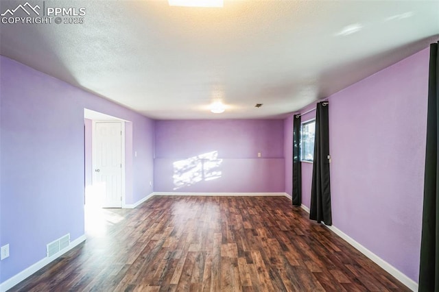 unfurnished room featuring dark wood-type flooring and a textured ceiling