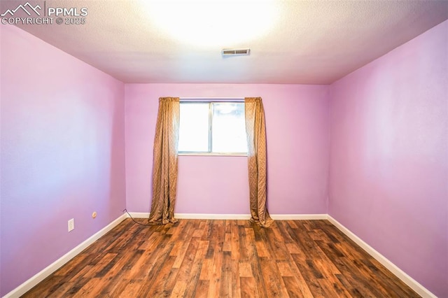 empty room featuring dark wood-type flooring and a textured ceiling