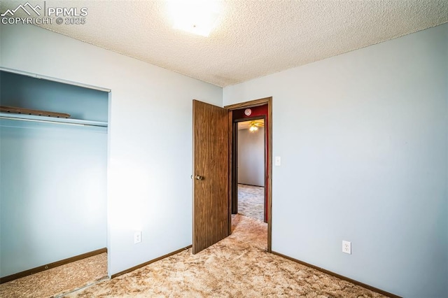 unfurnished bedroom with carpet, a textured ceiling, and a closet