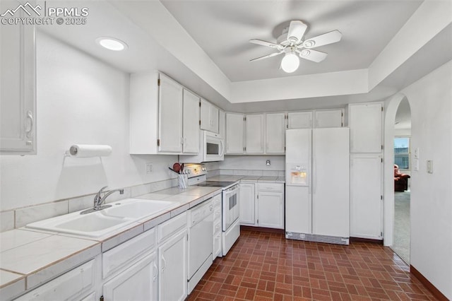 kitchen with white cabinetry, sink, tile counters, and white appliances