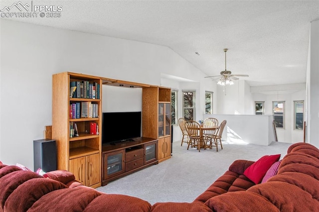 carpeted living room featuring ceiling fan, vaulted ceiling, and a textured ceiling