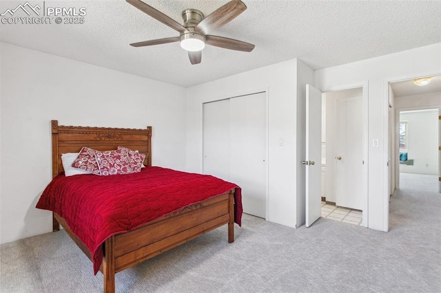 bedroom with ceiling fan, light colored carpet, a closet, and a textured ceiling