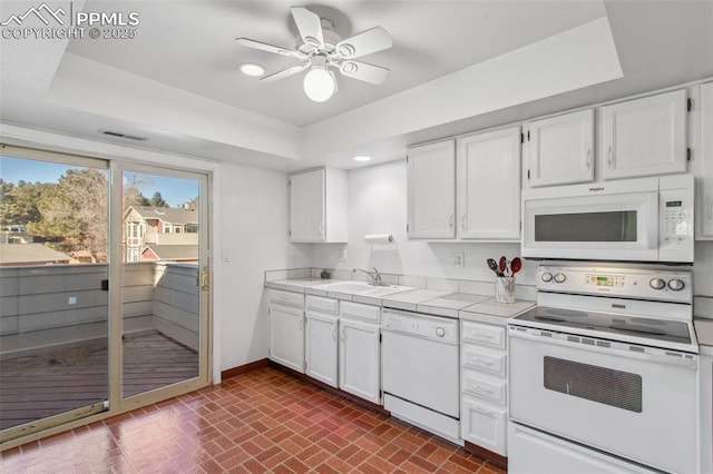 kitchen featuring sink, white cabinetry, ceiling fan, a tray ceiling, and white appliances