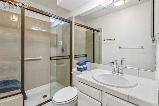 bathroom featuring a shower with door, vanity, and toilet