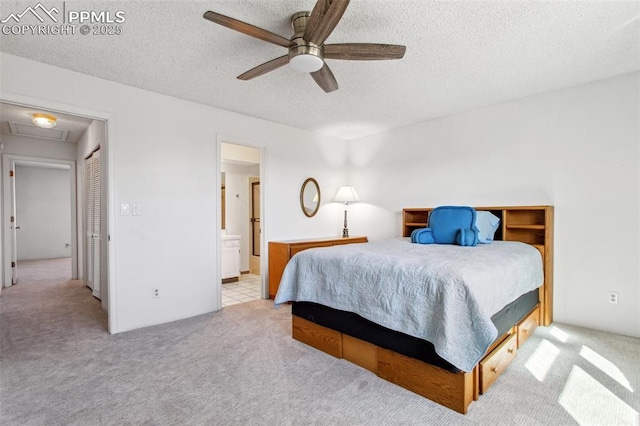 bedroom featuring ceiling fan, light carpet, a textured ceiling, and ensuite bath